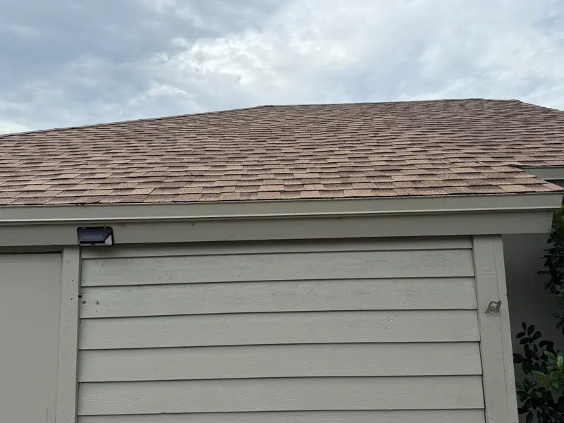 Customer photo: new tan architectural shingles over a garage wall after a roof replacement