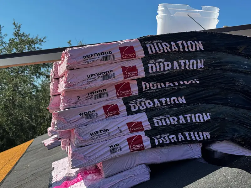 Bundles of new architectural shingles staged on a roof deck for a re-roof