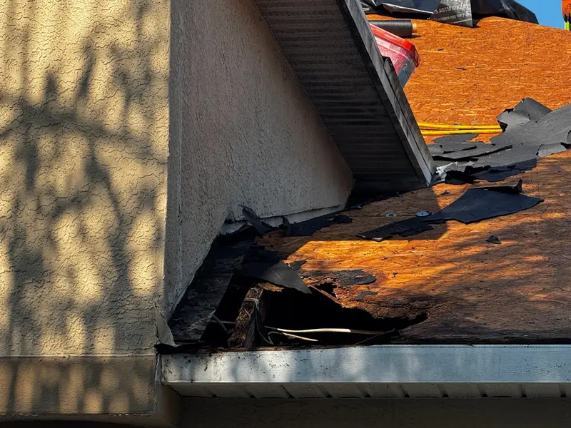 Eave during a tear-off: old shingle remnants, sheathing, fascia and gutter