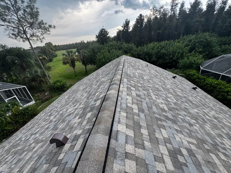 Finished gray shingle ridge on a re-roof by U First Roofing, a golf course fairway behind the house
