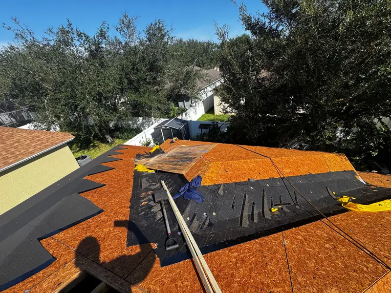 Tear-off in progress: old felt and shingles stripped back to the roof sheathing