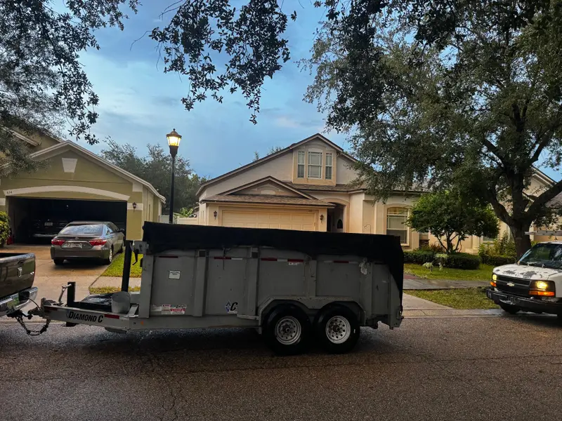U First Roofing dump trailer loaded and tarped in a driveway at the end of a roofing job