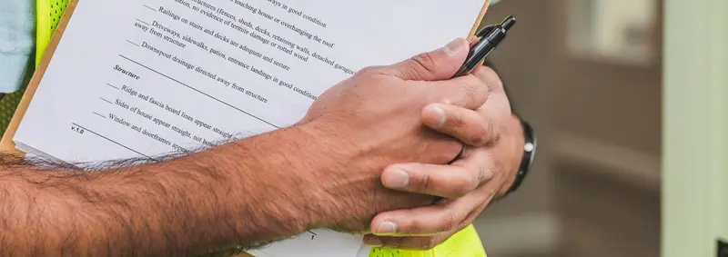 Hands holding a roof inspection checklist on a clipboard