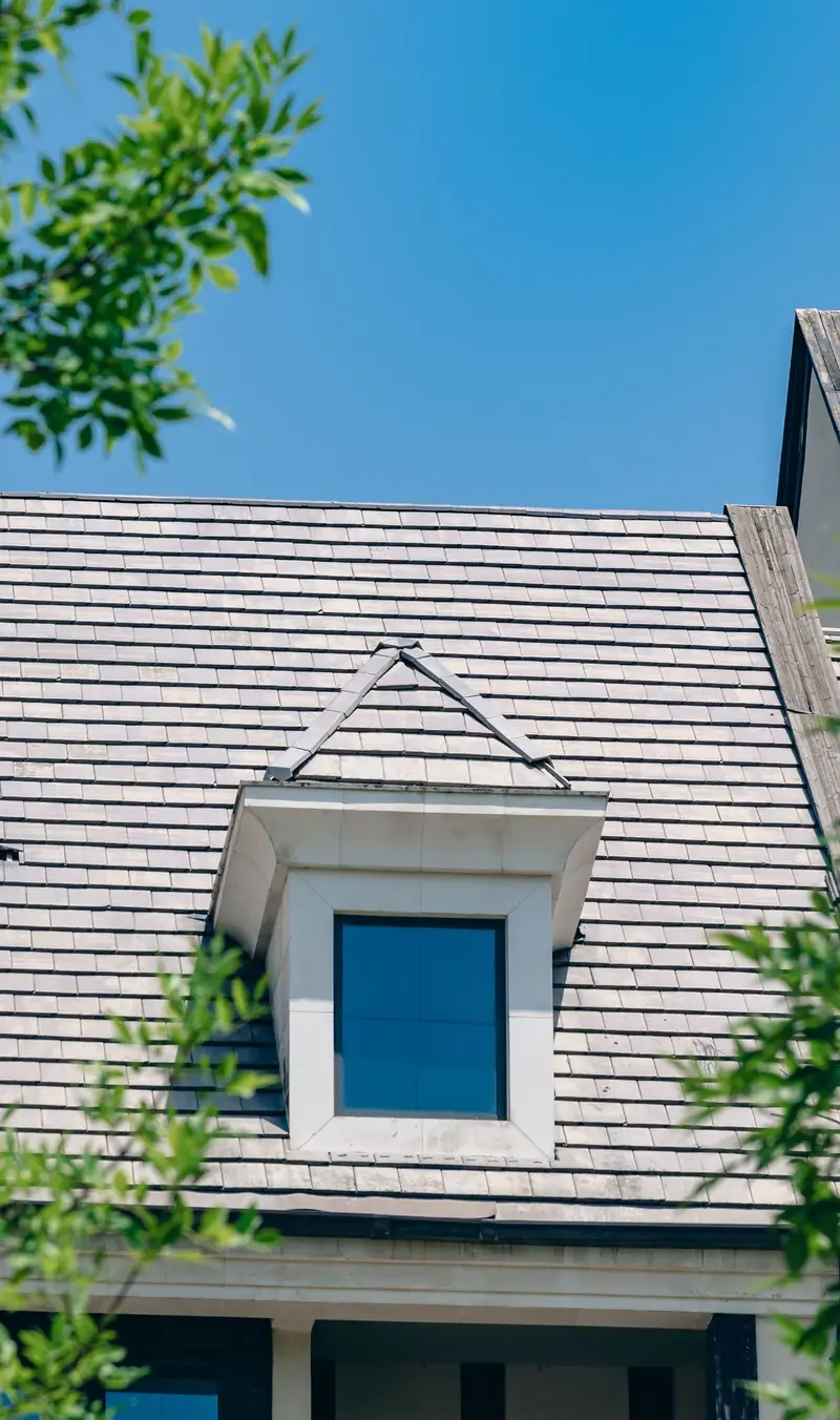 Gray shingle roof with a dormer against a blue sky