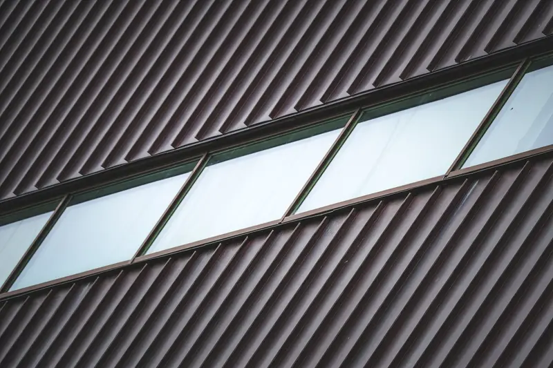 Dark ribbed metal roof panels with a skylight band
