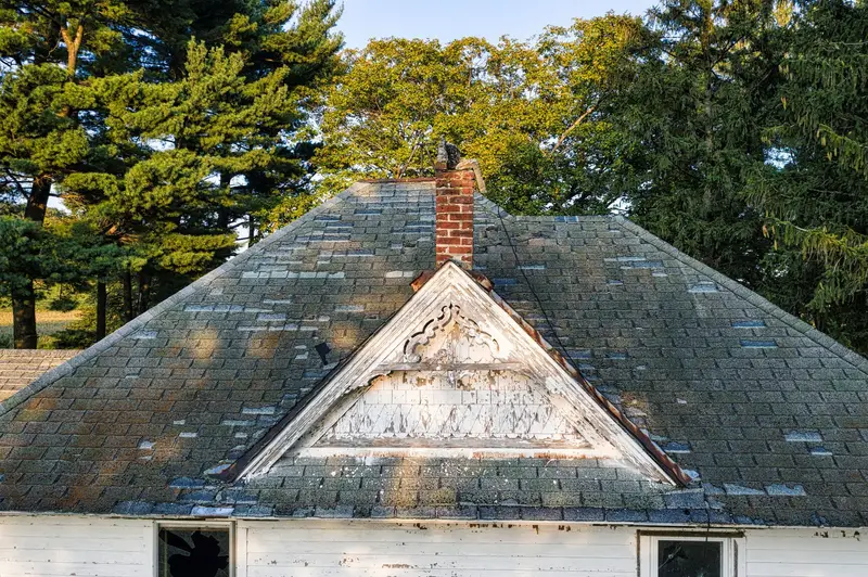 Worn, patchy shingle hip roof that is due for repair or replacement